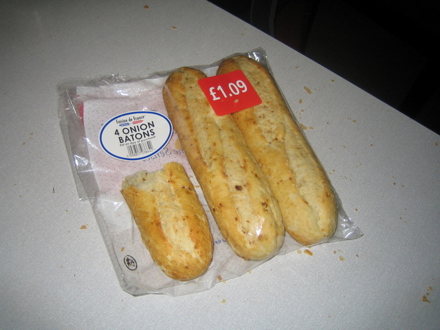 3 demi-baguettes dans leur emballage plastique, avec des etiquettes disant '4 onion batons' et '£1.09'
